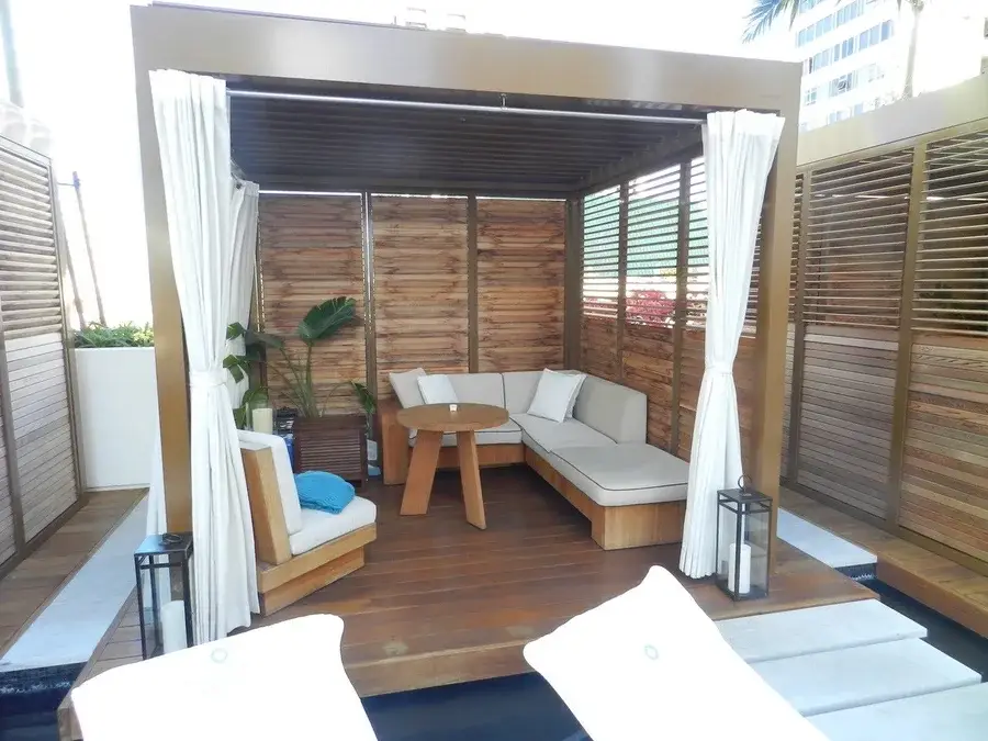 Luxurious cabana with wooden shutters on three walls and one open side.