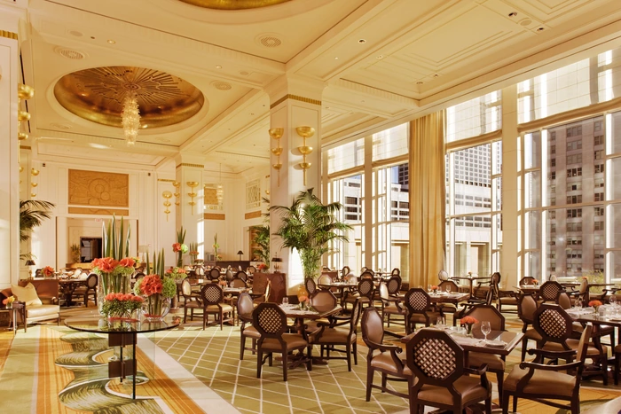 Large, traditional dining room with drapes and Roman shades on the large windows.