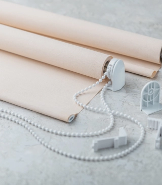 Peach-colored roller shade, disassembled on the ground.