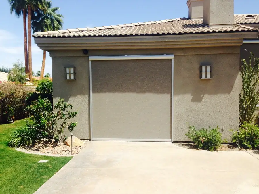 Exterior roller shade, fully lowered and color-matched to the wall of a home.
