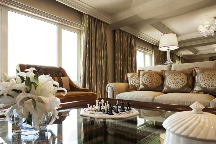 View of the living room of a hotel suite. There is a chessboard on the coffee table.
