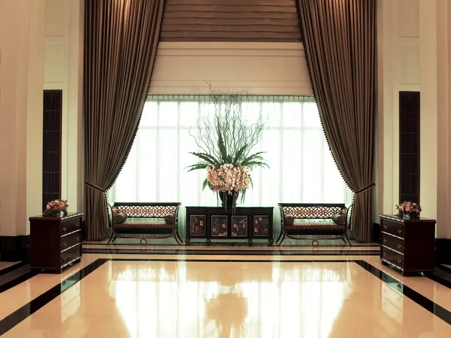 Foyer of a Bangkok hotel. A large window is framed by custom drapery.