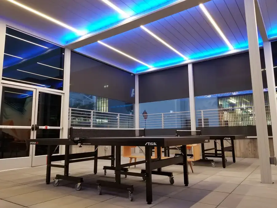 Outdoor patio with two ping pong tables, as well as custom shutters and roller shades.