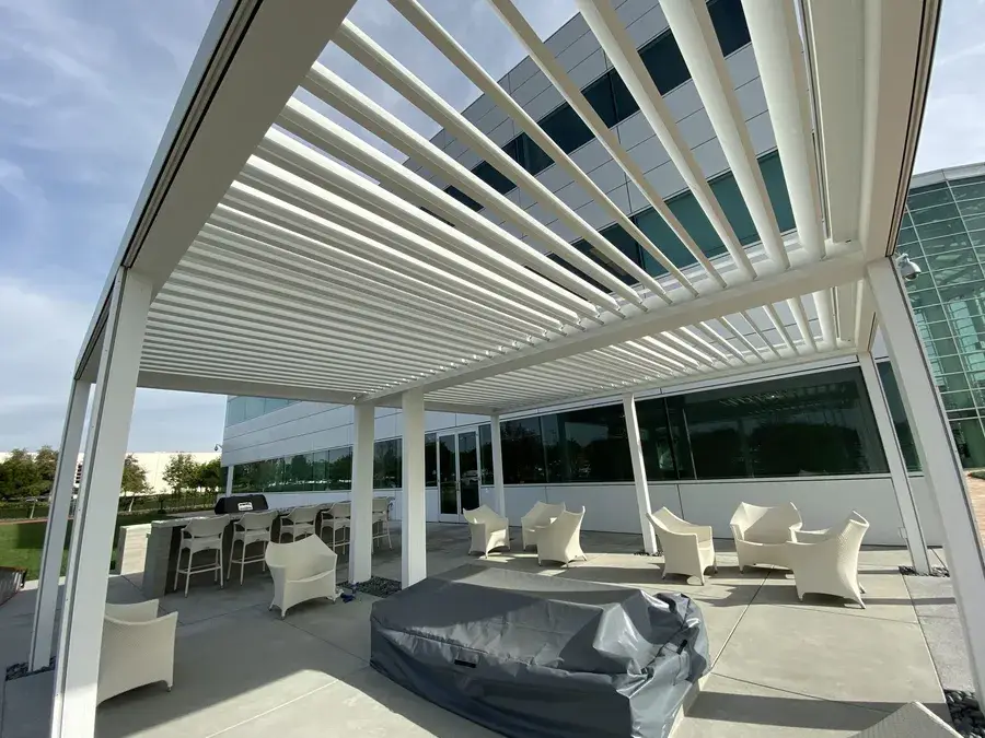 Wooden louvered patio shading structure covering several sets of patio furniture.